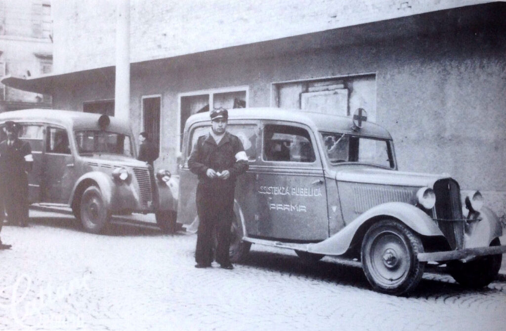 Foto storica di un milite di Assistenza Pubblica Parma con veicolo nel primo dopoguerra